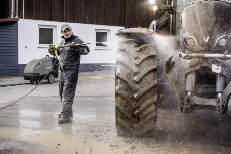 Pressure washer cleaning a muddy tractor.